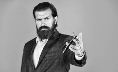 Sakallı adam eski saç jiletini tut. Kendine güvenen ve yakışıklı vahşi bir adam. Yüz bakımı. Sakallı, olgun bir hippi. Bıyıklı, vahşi, beyaz bir hippi. Erkek berber bakımı. Temiz ve kuru tıraş.