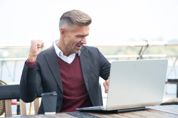 Rechtzeitig fertig geworden. Glücklicher Mann checkt Uhr und Laptop. Pünktlichkeit. Manager machen Gewinn — Stockfoto