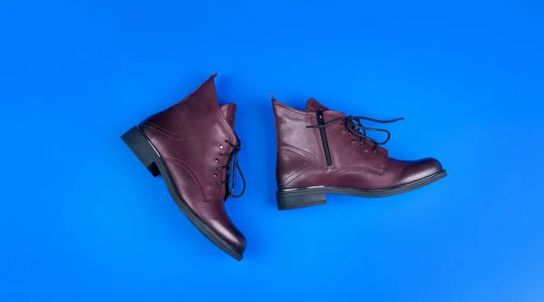 Стильные кожаные сапоги на голубом фоне, обувь — стоковое фото