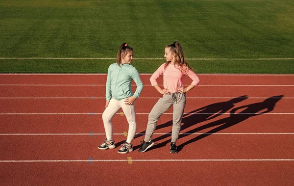 Κορίτσια παιδιά χαλαρώνουν μετά την προπόνηση του αθλητισμού έξω στην αρένα στάδιο, παιδική ηλικία — Φωτογραφία Αρχείου
