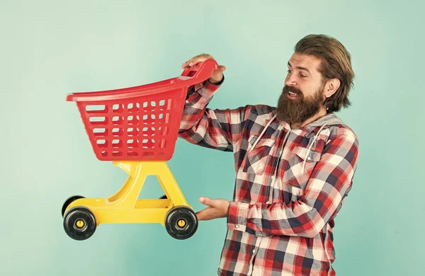 Başarılı bir alışveriş günü. Alışveriş arabalı bir erkek. Kareli gömlekli sakallı adam satın alır. Sakallı, traşsız, vahşi bir adam. Alışveriş merkezinden ürün al. günlük görevler ve rutin — Stok fotoğraf