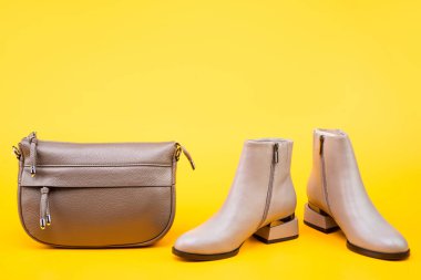 stylish leather boots and hat on yellow background with copy space, accessories