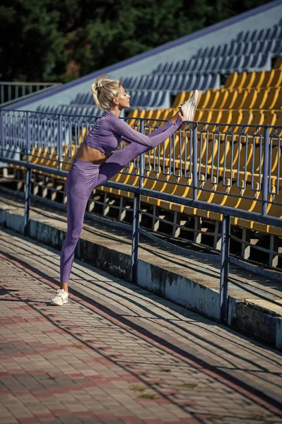 Sexy fitness mujer estiramiento en ropa deportiva en el estadio, estirar —  Fotos de Stock