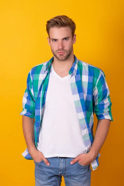 Handsome caucasian guy pose in checked shirt keeping hands in pockets yellow background, casual — 스톡 사진