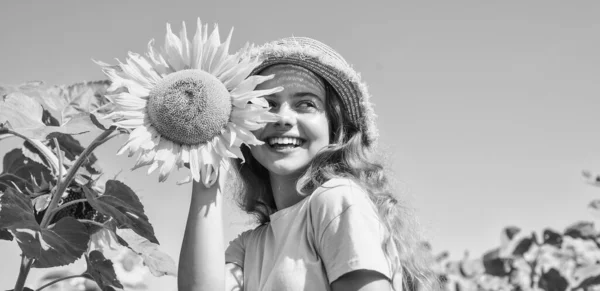 Élj fényesen. Egy kislány a nyári napraforgómezőn. Boldog gyermeknapot! Gyerekkori boldogság. boldog gyerek portréja gyönyörű napraforgóval. vidám gyermek szalmakalapban sárga virágok között — Stock Fotó