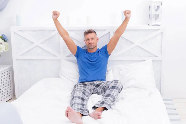 Happy man in pajamas wakeup stretching after sleep in bed, morning — Stockfoto
