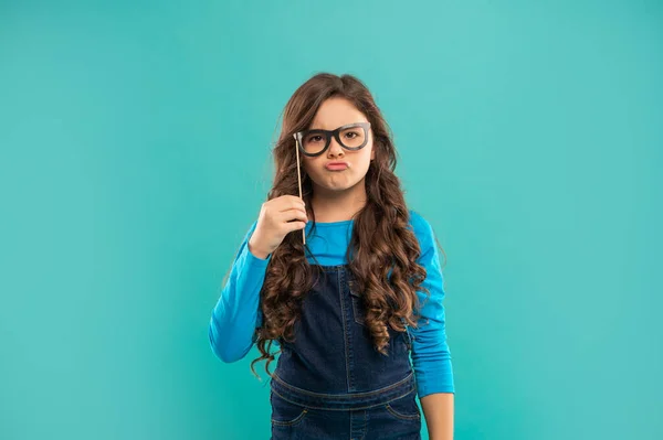 Serious funny teen girl has curly hair hold party accessory of glasses, party time — Stockfoto