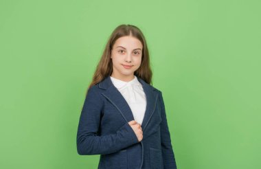 smiling child in school uniform on green background, school