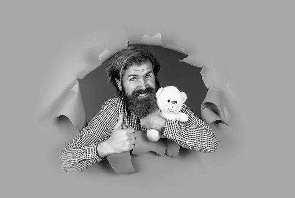 Зрілий бородатий хлопець має довге волосся з подарунковою іграшкою ведмедя на свято, найкращий подарунок — стокове фото
