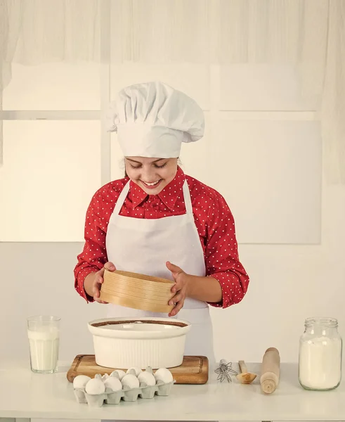 Schauen Sie, was kocht. glücklich Teenager Mädchen Teig kochen. Kind in Kochuniform. Kulinarik und Küche. — Stockfoto