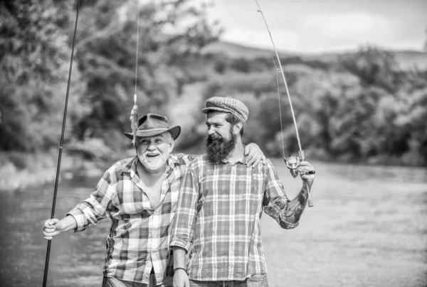 Tiempo en familia. Actividad y hobby. Pesca de agua dulce lago estanque río. Pescador con caña de pescar. Hombres barbudos capturando peces. Hombre maduro con amigo pescando. Vacaciones de verano. Gente alegre feliz —  Fotos de Stock