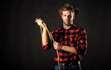 Batı hayatı. Erkek traşsız kovboy siyah arka planı. Şapka tutan adam. Amerikan kovboyunun kementi. Lasso, rodeo yarışmaları kullanırdı. Kementle bağlanabilir ya da paketlenebilir. Acımasız ve kendinden emin.