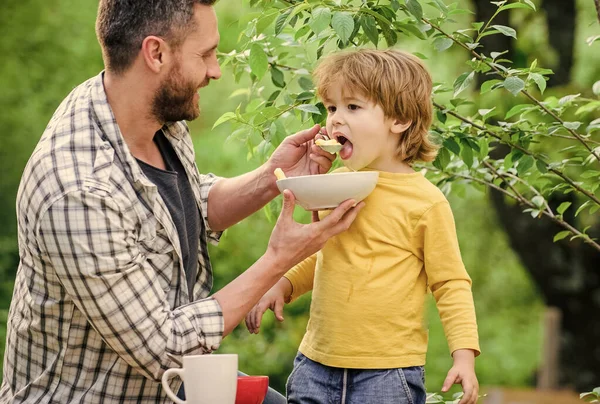 Son and father eating outdoor. Morning breakfast. Tasty food. healthy food and dieting. Dairy products. happy fathers day. Little boy with dad eat cereal. family rest time. Weekend with family — Stock Photo, Image