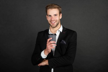 happy handsome young man in suit with takeaway coffee