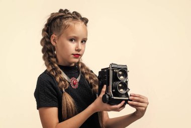 Yeni kameram. Geçmişi olan neşeli kız beyazda izole edilmiş görünüyor. Çocuk modası. Çocuk retro kamerayla fotoğraf çekiyor. Güzellik ve moda. Gazeteci ya da muhabir fotoğrafları. çocukluk mutluluğu
