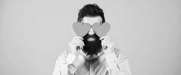 Ik ben in een rare bui. Een man met een baard die ogen bedekt met harten. Hipster met kleine rode hartjes. Fijne Valentijnsdag. Sexy Valentijn man met hartvormige decoraties. De vakantie van liefde en romantiek — Stockfoto