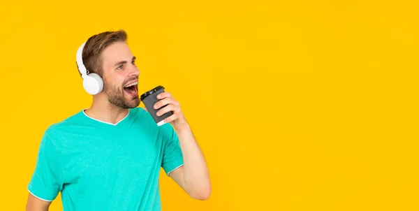 Cantando chico con cerdas escuchar música beber café sobre fondo amarillo, música — Foto de Stock