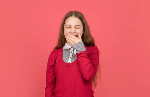 Сонная зевающая девочка-подросток в школьной форме на красном фоне, детство — стоковое фото