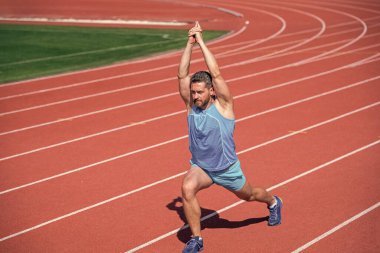 Erkek koşucu sporcu antrenman yapıyor ve dışarıda egzersiz yapıyor, esniyor.