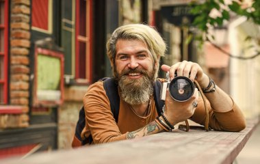 Modern iş. Eski teknoloji. Profesyonel fotoğrafçı klasik kamera kullanır. Fotoğrafçılık işi. Sakallı hippi adam fotoğraf çekiyor. Gazeteci gazeteci. Geçmişe dönük kamerası olan zalim bir adam.