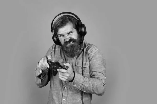 Hipster caucasiano com barba e cabelo elegante no fone de ouvido com console de jogos, vida moderna — Fotografia de Stock