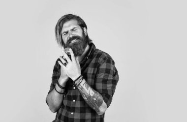 Modern görünümlü sakallı hippi mikrofonlu. Müzik konsepti. Bıyıklı vahşi yakışıklı adam şarkı söylüyor. Olgun adam mikrofonda şarkı söylüyor. Karaoke. Sıradan moda stili şarkıcı