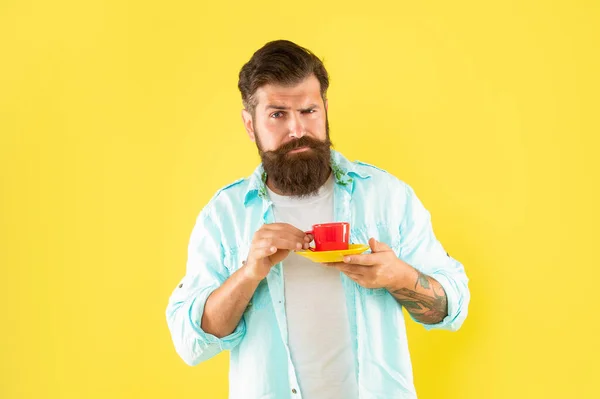 Серьезный бородатый человек пить утренний кофе на желтом фоне, утром — стоковое фото