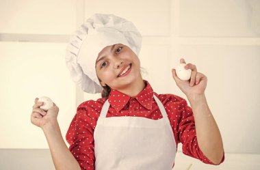 Özel yemek yapıyorum. Yumurta tutan mutlu genç kız. Çocuk pastanede şef üniforması giyiyor.