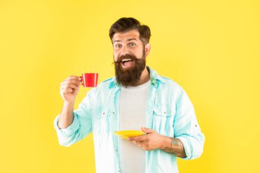 Elinde çay tabağı sarısı arka planda kahve içen mutlu adam, kır.