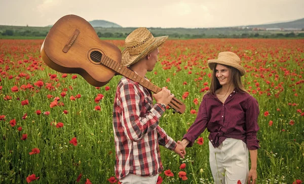 Aşık mutlu çift, akustik gitarlı, akrabaları olan gelincik çiçeğinin güzel tarlasında rahatlar. — Stok fotoğraf