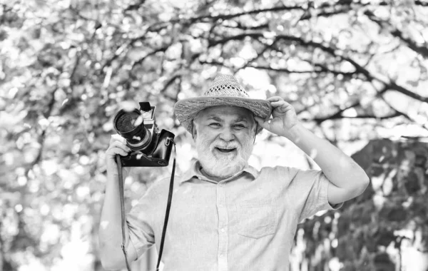 Bahar geldi. Yaşlı sakallı adam pembe çiçeklerin fotoğrafını çekiyor. Profesyonel fotoğrafçı tasarımcısı. Mutlu emeklilik. Turist, kamera kullanarak kiraz çiçeklerinin fotoğrafını çeker. Tam çiçeklenme fotoğrafçılığında sakura — Stok fotoğraf