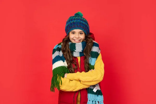 Zadowolony nastolatek dziewczyna w dzianiny czapka zimowa i szalik na czerwonym tle, sezon mody — Zdjęcie stockowe
