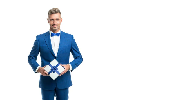 Χαρούμενος άνθρωπος σε μπλε κοστούμι παπιγιόν κρατήσει το παρόν κουτί απομονώνονται σε λευκό με αντίγραφο χώρο — Φωτογραφία Αρχείου