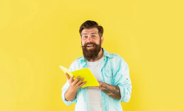 Bärtiger Mann überrascht mit Buch auf gelbem Hintergrund, Überraschung — Stockfoto