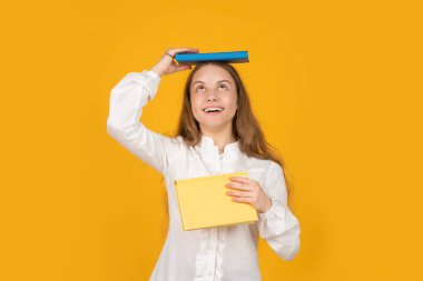 Genç kız ödevlerini defterle yapıyor. Çalışma kitabıyla çalış. Şaşırmış çocuk kitabı.