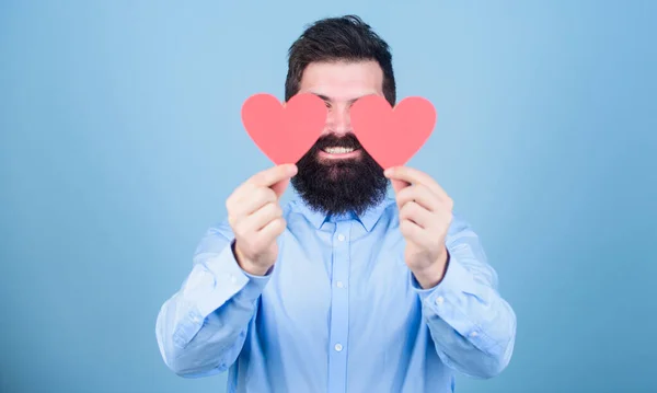 Guardando il suo amore. Sexy uomo di San Valentino che copre gli occhi con carte d'amore. Hipster con i cuori piccoli. Un uomo barbuto con i cuori rossi. Buon San Valentino. Esprimendo il suo amore — Foto Stock