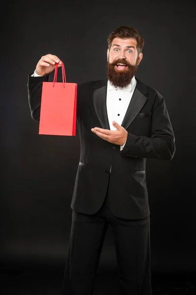 Hombre sorprendido en esmoquin pajarita presentando bolsa de compras. San Valentín. espacio de copia. — Foto de Stock