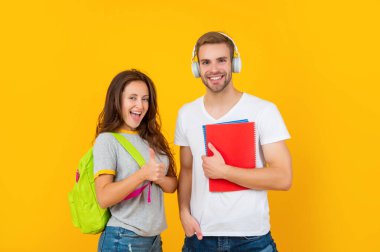 Çalışma kitabı ve sırt çantasıyla mutlu iki öğrenci baş parmağını kaldırdı, eğitim gördü.