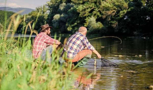 Deux amis mâles pêchant ensemble. pêche au gros gibier. relaxer sur la nature. heureux pêcheurs amitié. père retraité et fils barbu mature. voler poisson passe-temps des hommes. pêche à la retraite. Nous l'avons attrapé — Photo