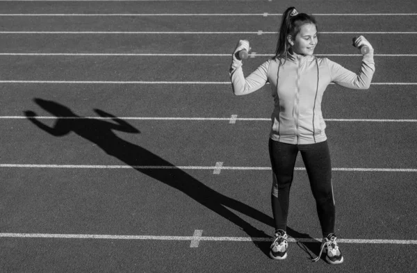 Zdravé dítě dívka trénink fitness s činkami na stadionu běžecké dráhy, vážení zvedání — Stock fotografie