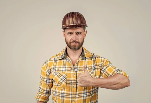 Garantire la qualità. architetto uomo con pollice in su. Il tipo indossa l'uniforme da operaio. bello costruttore in casco. maturo uomo indossare camicia a scacchi. costruttore professionista o meccanico. ingegnere costruttore di successo — Foto Stock