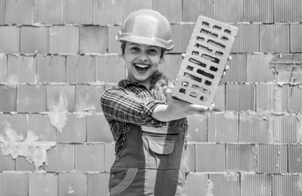 보호용 헬멧을 쓰고 벽돌을 사용하여 건물을 짓는 십 대 소녀 — 스톡 사진