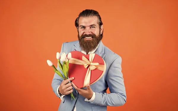 Взрослый бородатый мужчина выглядит элегантно с весенними тюльпанами, свидание — стоковое фото