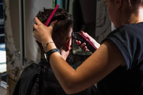 El tipo es una apariencia caucásica de pelo oscuro en un corte de pelo en una peluquería, peluquería — Foto de Stock