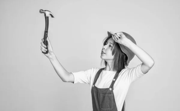 Niña usando uniforme y casco mientras trabaja en taller con martillo, industria — Foto de Stock