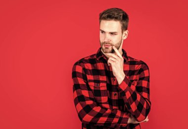 Şık bir erkek günlük kıyafetler giyer. Tıraşsız suratlı kıllı sakallı adam. moda ve güzellik. Berber dükkanı konsepti. Erkekler giyer. Kırmızı kareli gömlekli genç yakışıklı adam. Boşluğu kopyala