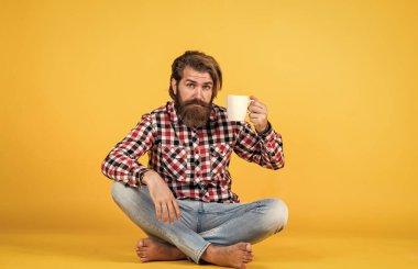 Tıraşsız sakallı yakışıklı ve şık saçlı sıradan kıyafetler giyen kahve içen, şerefe.