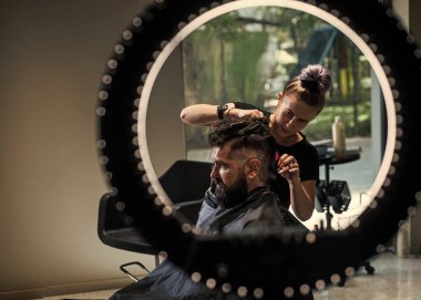 Berber ustası saç kesti. Kuaförde sakallı, olgun bir hippi. Bıyıklı hippi yeni saç stili yapıyor. Berber dükkanı. Erkek saç stili. Tıraş bıçağıyla mükemmel saç kesimi. Profesyonel seçim.