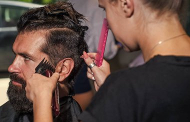 Profesyonel berber ustası olan acımasız adam elektrikli tıraş makinesi kullanıyor. Hipster. Erkek berber bakımı. Kuaför salonundaki sakallı adam. Güzellik ve moda. Saç ve sakal. Taze funky güzellik