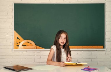 Okula dönüyorum. Genç kız tahtaya yakın bir sınıfta çalışıyor. Neşeli çocuk konuyu öğreniyor. Modern eğitim. Bilgi günü. Çocuk öğrenci masada oturur. Kız üniversite öğrencisi.